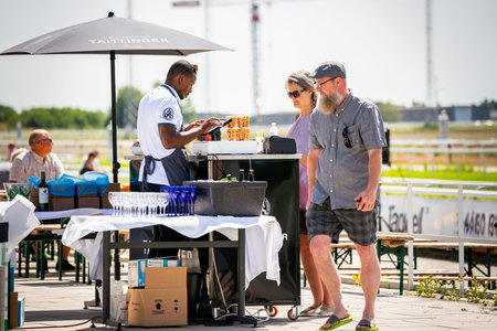 BRO, SWEDEN - JUNE 30, 2019: Customers and staff at an outdoor restaurant with a drink stand,...