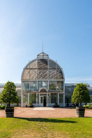 GOTHENBURG, SWEDEN - JULY 17, 2019: Outdoor summer facade front view o a big beautiful glass greenhouse  with incidental people in the foreground at the public Palm House, Garden Society in Gothenburg Sweden July 17, 2019.のeditorial素材
