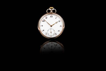 Front view of old antique mechanical golden steel pocket watch isolated on black background.の写真素材