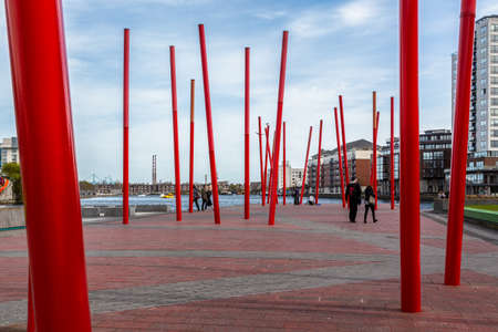 DUBLIN, IRELAND - APRIL 21, 2016: City view of public contemporary modern art with tall red poles in the Dockland area in Dublin Ireland April 21, 2016. Incidental people in the background.のeditorial素材