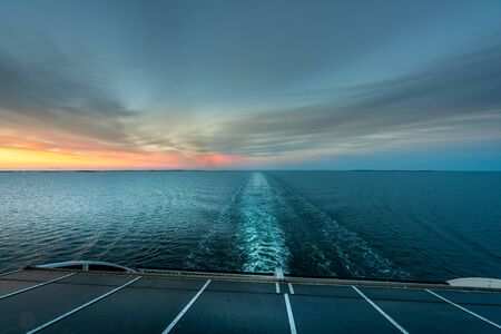 Beautiful sunset ocean view of the horizon with ship's wake seen from the back of a cruise ship.の写真素材