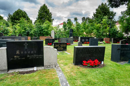 TURKU, FINLAND - JULY 13, 2016: Summer view of an open city park cemetery with black inscribed gravestones. Residential area with surrounding green trees in Turku Finland July 13, 20Â§16.のeditorial素材