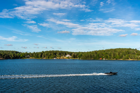 Summer seaside landscape view of a fast going speedboat with blue sky and land horizon in the...