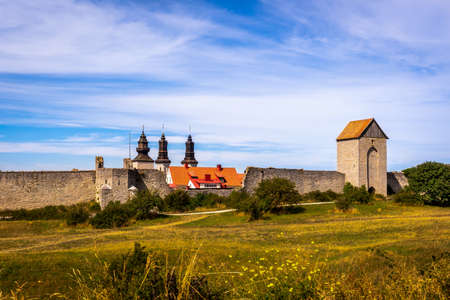 Beautiful rural summer view of an ancient medieval brick tower and defense wall surrounding the city of Visby Gotland, Sweden. Blue sky and grassy fields.のeditorial素材