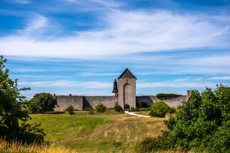 Beautiful rural summer view of an ancient medieval brick tower and defense wall surrounding the city of Visby Gotland, Sweden. Blue sky and grassy fields.のeditorial素材