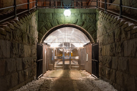 Beautiful night scene of massive stone wall and arch with bright lamp over pedestrian underground tunnel entrance in Stockholm Sweden.の写真素材