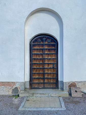 Outdoor front view of beautiful old wooden door entrance with black iron fittings and white stone building.の写真素材