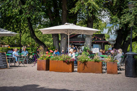STOCKHOLM, SWEDEN - JULY 20, 2021: Beautifrul summer garden view of a small cafe with guests in the public city garden KungstrÃ¤dgÃ¥rden in Stockholm July 20, 2021.のeditorial素材