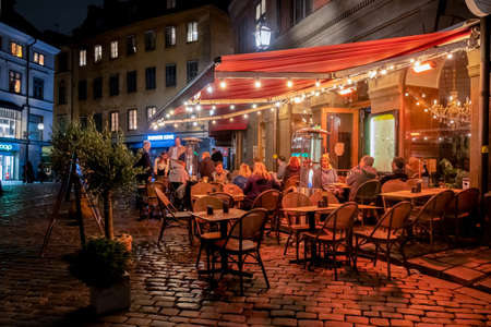 STOCKHOLM, SWEDEN - AUGUST 27, 2021: Night scene with guests eating and drinking at a restaurant outdoors in Gamla Stan Stockholm Sweden August 27, 2021.のeditorial素材