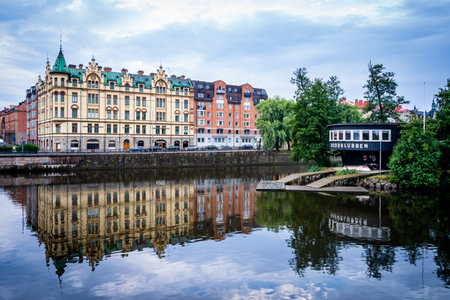 NORRKOPING, SWEDEN - JULY 27, 2021: Beautiful cityscape view of a old black vintage boathouse with...