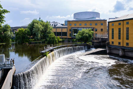 Industrial cityscape with old factory buildings and and water reservoir with waterfall in Norrkoping Sweden.のeditorial素材