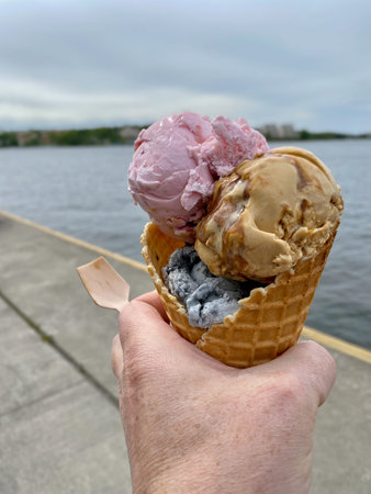 Closeup of hand holding ice creme waffle otuurdoors in stockholm Sweden with water and sky.