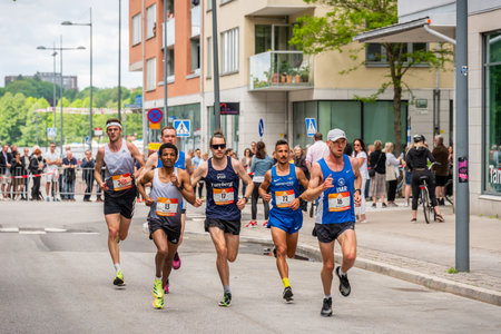 STOCKHOLM, SWEDEN - JUNE 4, 2022: City street front view of runners at Stockholm Marathon with incidental people in Stockholm Sweden June 4, 2022.のeditorial素材