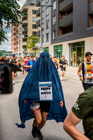 STOCKHOLM, SWEDEN - JUNE 4, 2022: City street front view of covered muslim protest runner at Stockholm Marathon with incidental people in Stockholm Sweden June 4, 2022.のeditorial素材