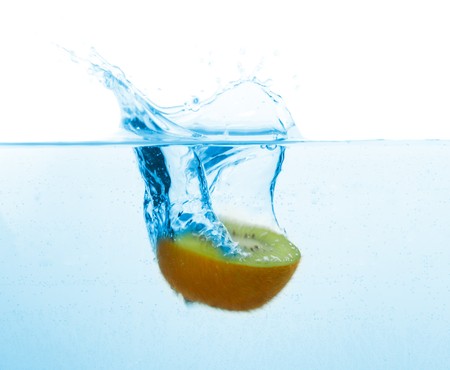 kiwi falling into blue water with splash, isolated on whiteの写真素材