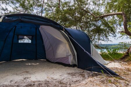 Big six person tent on the beach, blue grey, trees and ocean in the backgroundの写真素材