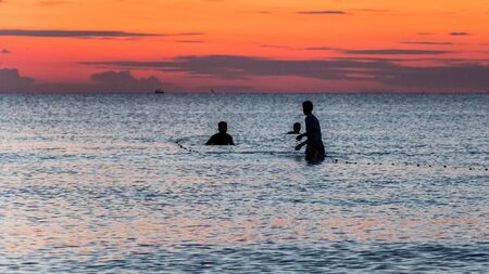 Three fisherman are fishing at Sunset on Koh Rongの写真素材