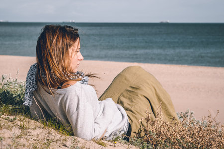 Young girl, wearing casual clothes, photographed on the beach in winter.