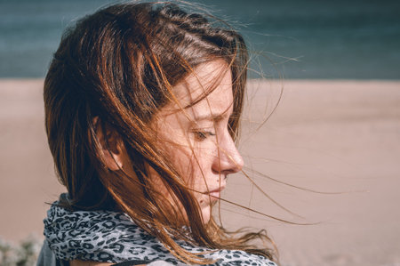 Young girl, wearing casual clothes, photographed on the beach in winter.