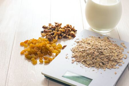 oatmeal raisins walnut milk scale on a wooden tableの写真素材