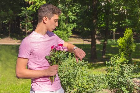 young men waiting date with roses watching timeの写真素材