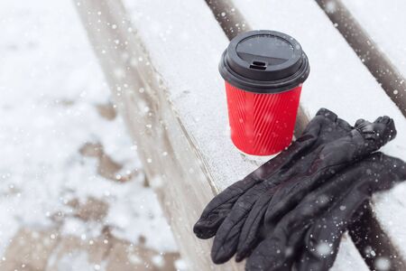 paper coffee cup and gloves laying on a park bench on the winter dayの写真素材