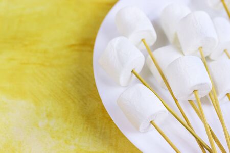 marshmallows on a sticks, laying on a white plate. prepared for fondue.の写真素材