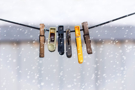 old clothespins on a rope hanging outside house, winter time and snowfall