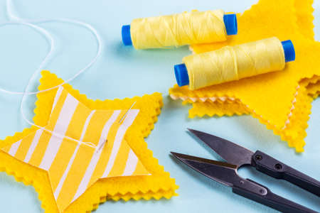sewing star figures from yellow felt, materials on a light blue backgroundの写真素材