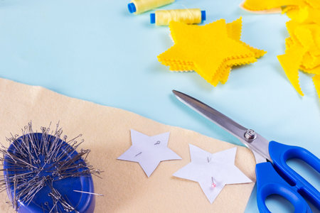 sewing star figures from yellow felt, materials on a light blue background