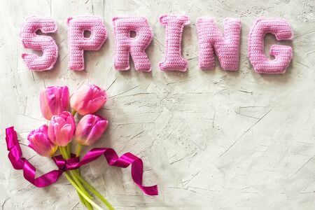 tulip floweres and spring word from knitted letters on gray backgroundの写真素材