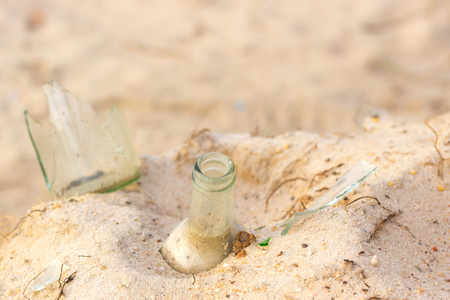 Broken beer glass bottles on a sandの写真素材