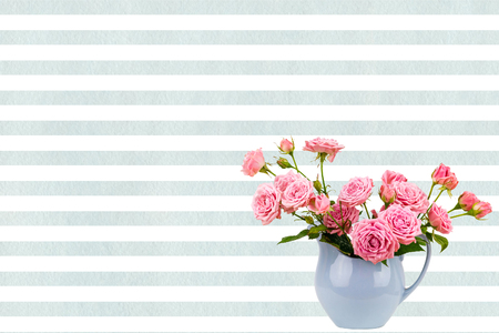 Pink flowers in blue jug on watercolor blue stripes background.の写真素材
