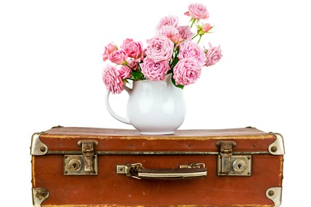 Flowers in jug on old brown vintage suitcase.の写真素材