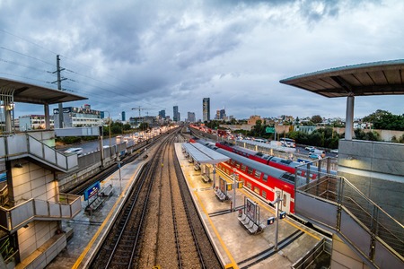 TEL AVIV, ISRAEL - November, 2016: View to the railway station and red train over new skyscrapers in Tel Aviv in the evening.のeditorial素材