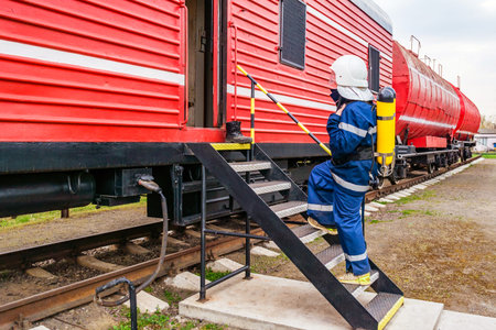 Fireman wearing protective uniform and safety helmet standing next to a fire train.