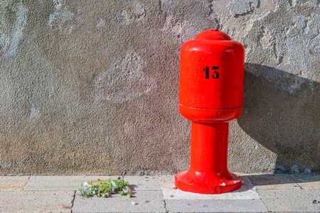 Number 13 on a bright red pillar in front of a beige wall.の写真素材