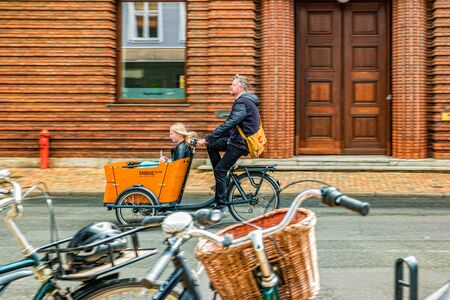 Odense, Denmark - May, 2019: Street life in Odense. Man riding bicycle with trailer for children.の写真素材