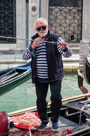 Venice, Italy - October, 2019: Gondolier on a gondola on canal street in Venice, Italy.のeditorial素材