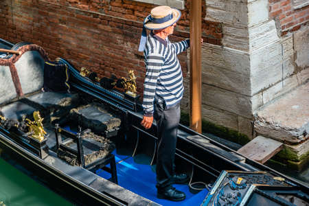 Venice, Italy - October, 2019: Gondolier in gondolier hat on canal street in Venice, Italy.のeditorial素材