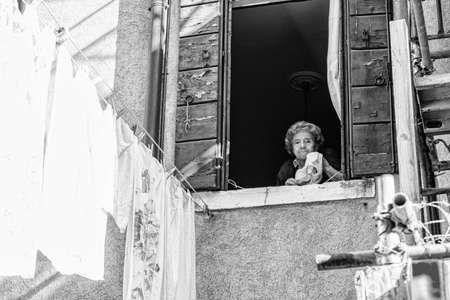 Venice, Italy - October, 2019: Elderly Italian woman hanging out clothes.のeditorial素材