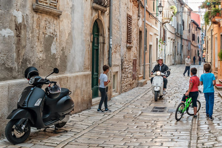 Rovinj, Croatia - October, 2019: Street life in Rovinj. Children and man riding a scooter.の写真素材