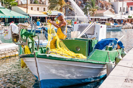 Symi, Greece - June 2021: Fisherman repairing fishing net on Symi Island near Rhodes, Greece.のeditorial素材