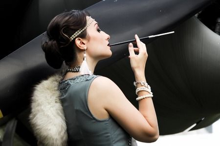 Retro portrait of woman with mouthpiece and fur and airplane propeller at the backgroundの写真素材
