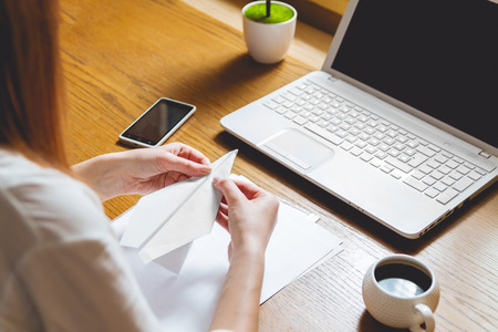 businesswoman in modern office takes a break and prepares a paper airplaneの写真素材