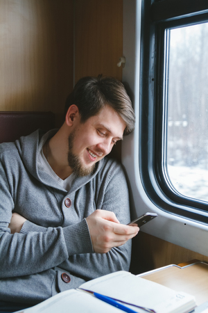 The man sits at a table in a train, writes smsの写真素材