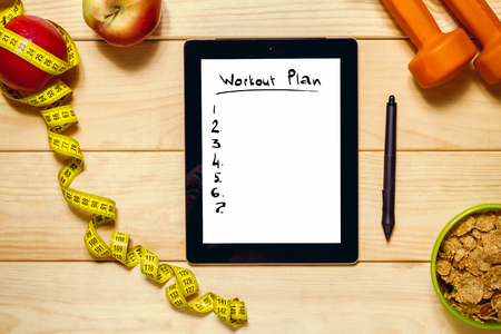 Fitness concept. Still life of apples, dumbbells, flakes and the plate and tape measure on a wooden background. top viewの写真素材