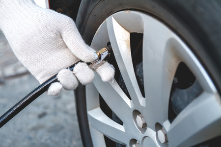 Pumping car tires in the service station. People at work. The man inflates car tiresの写真素材