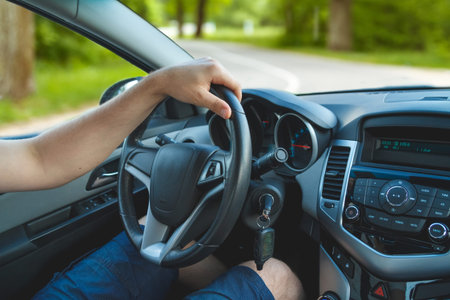 Young man driving a car. Close-up of a steering wheel