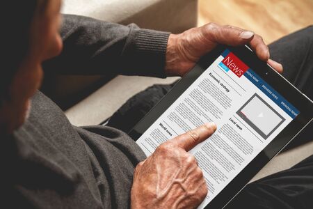 Senior reading news on tablet. Looking informationの写真素材